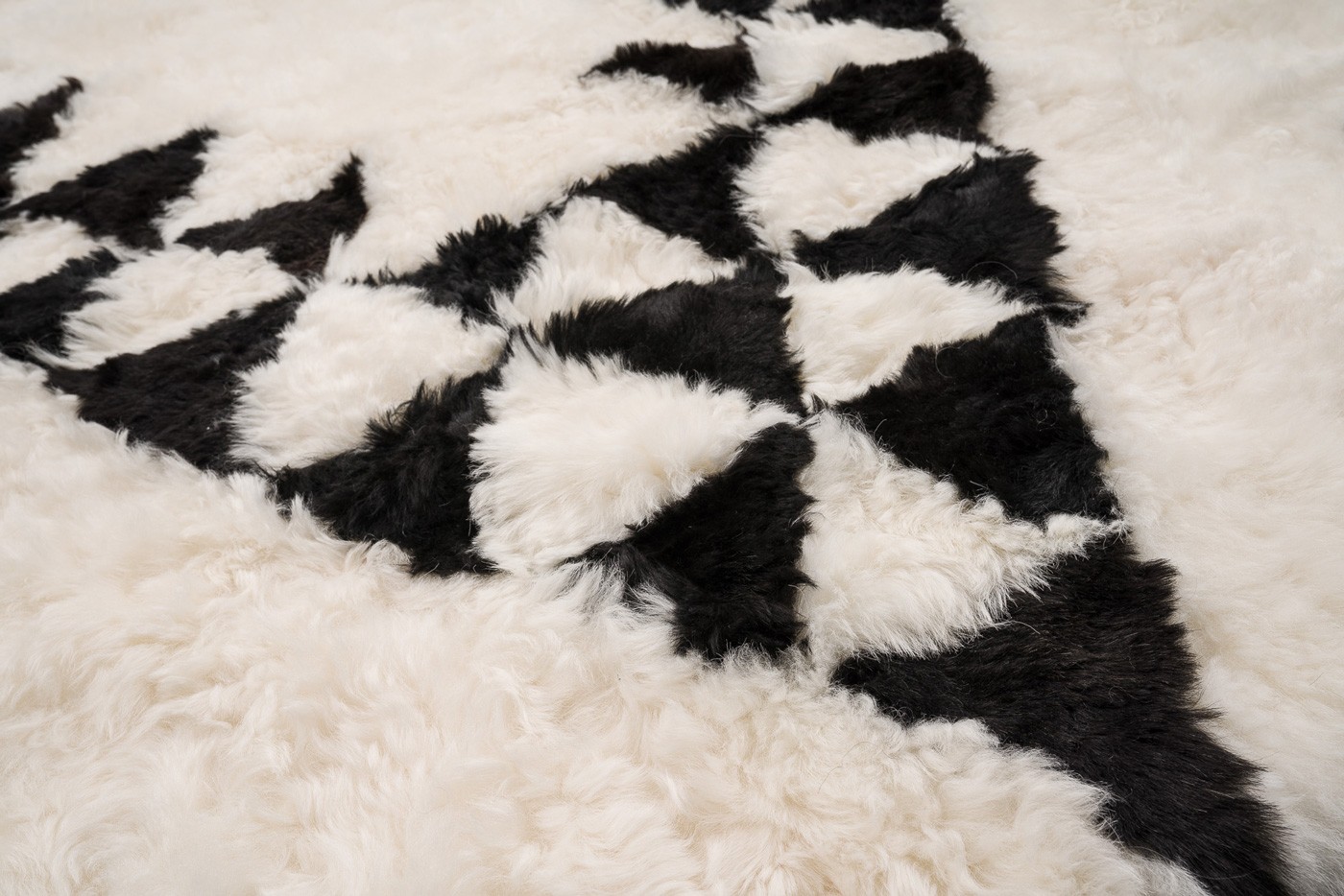 Un motif Berbère assumé très délicat pour ce tapis haut-de-gamme en peau de mouton blanche et noire fabriqué dans nos ateliers de Strasbourg