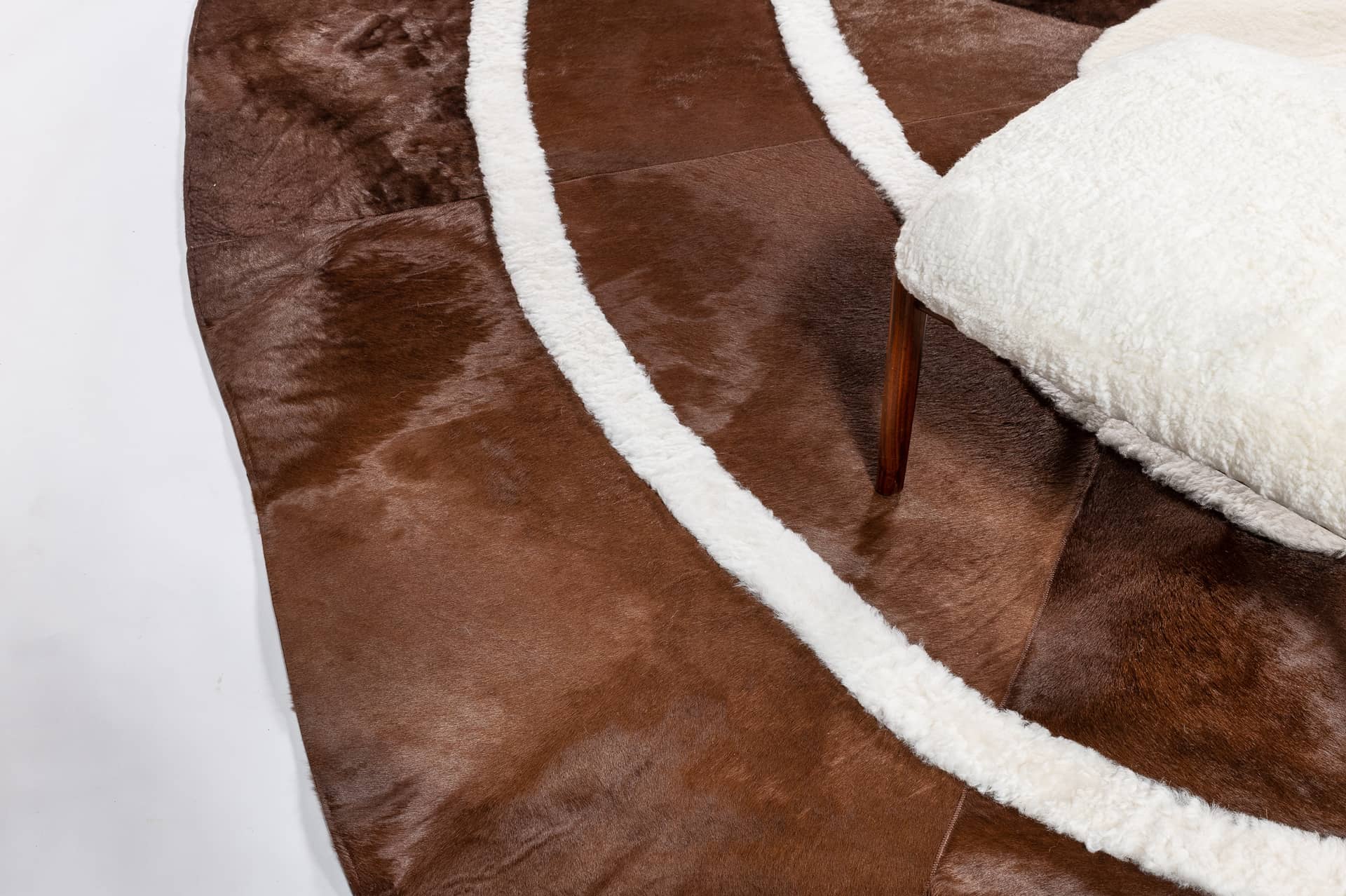 Une jolie forme organique pour ce modèle exclusif de tapis en peau de vache marron et bordures de mouton blanc rasé.