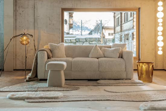 Scénographie de notre showroom de Gstaad avec canapé et pouf  blanc en agneau et tapis blanc en peau de vache