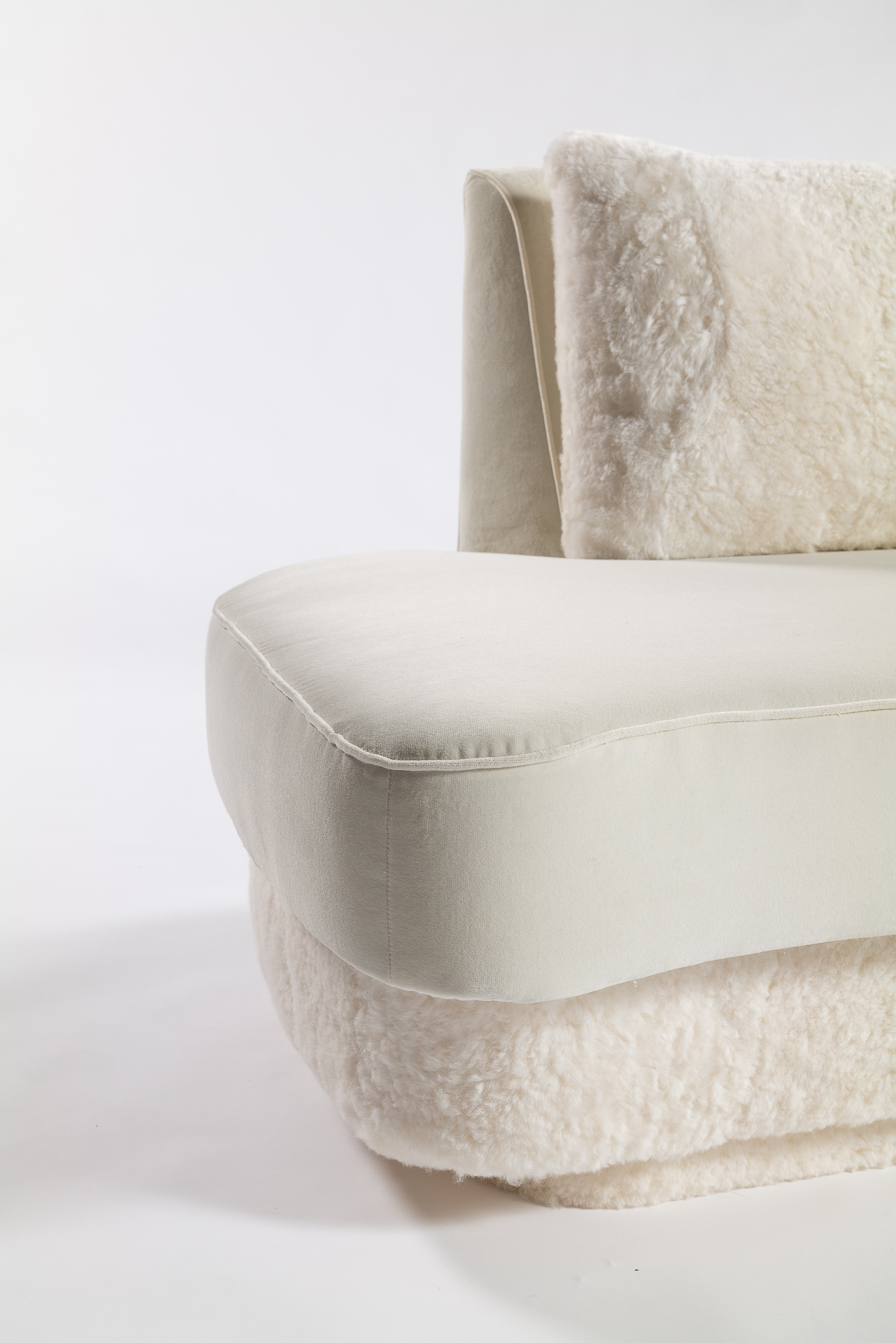 Canapé blanc recouvert de velours avec quelques détails luxueux d'un piétement et de coussins d'assise en agneau