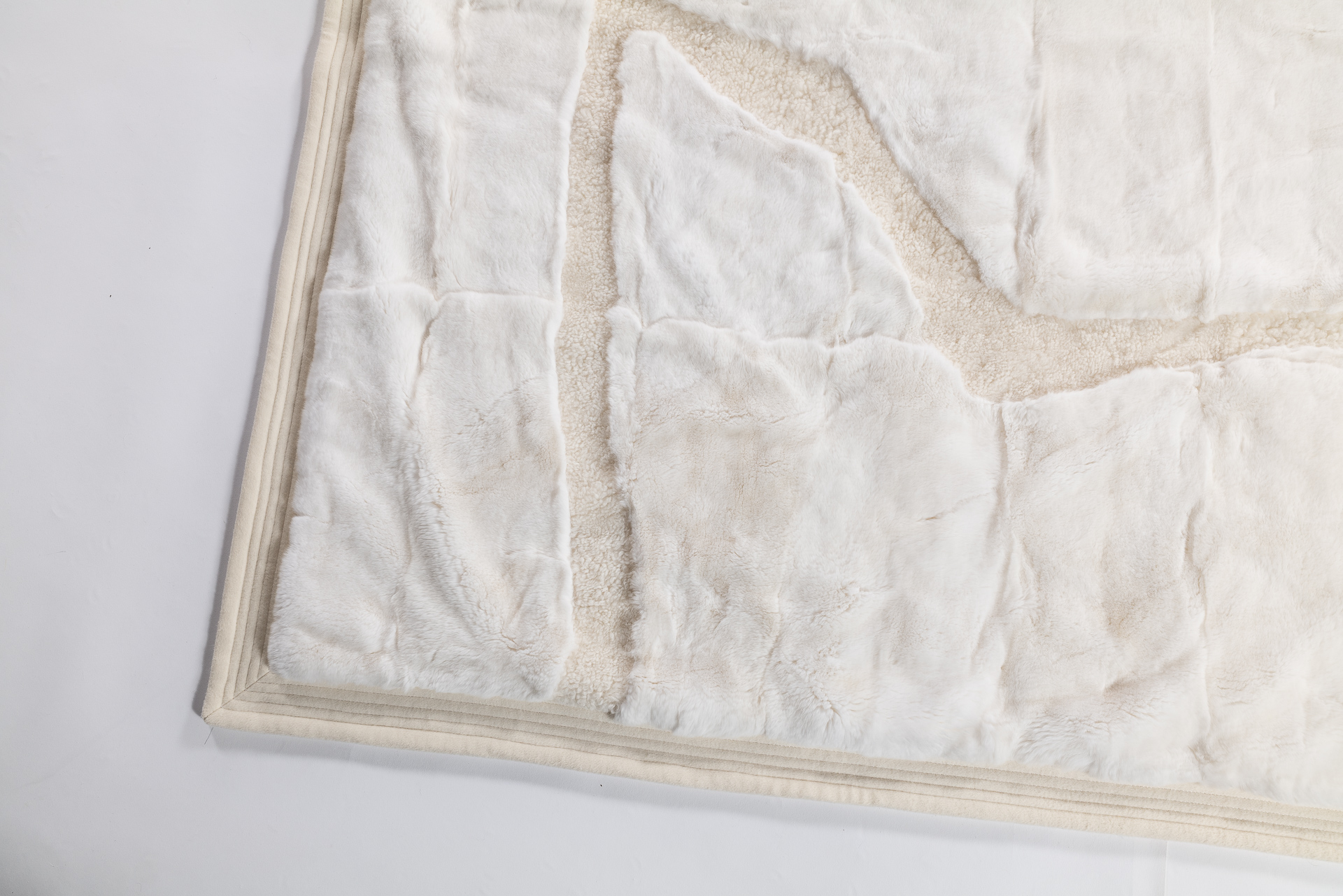 Détail luxe d'un plaid blanc avec bordure surpiquée en cachemire. Plaid fabriqué sur-mesure dans nos ateliers en FRANCE