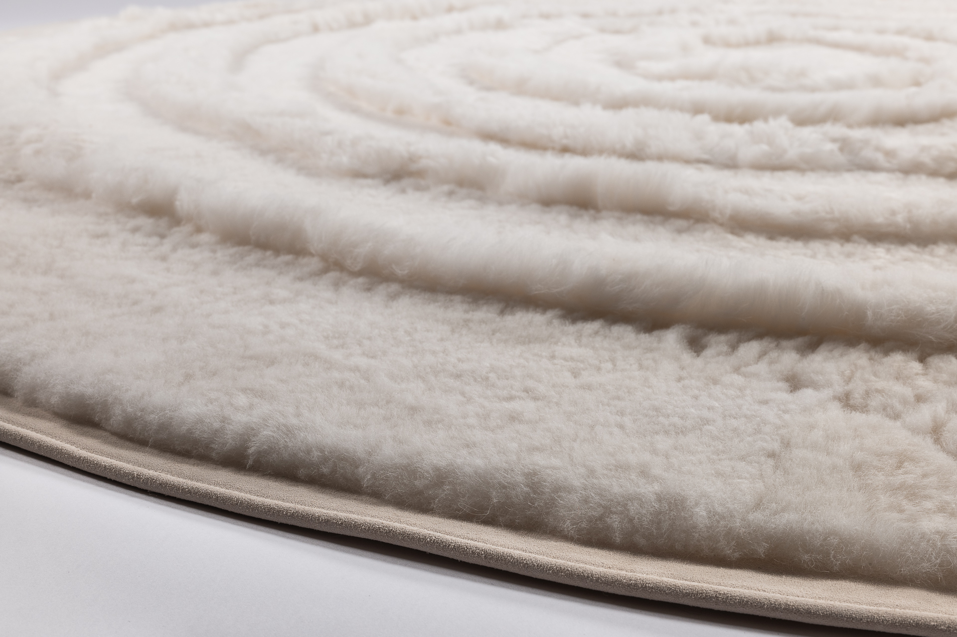 Tapis rond en mouton blanc gansé d'une bordure en nubuck de coloris assorti. Un tapis design et contemporain Made in France fabriqué sur-mesure